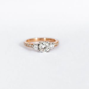 18ct rose gold ring with a 1.02ct round brilliant cut diamond as the centre stone. Two diamonds equalling 0,21ct make up this trilogy in a band of 0,018ct diamonds.