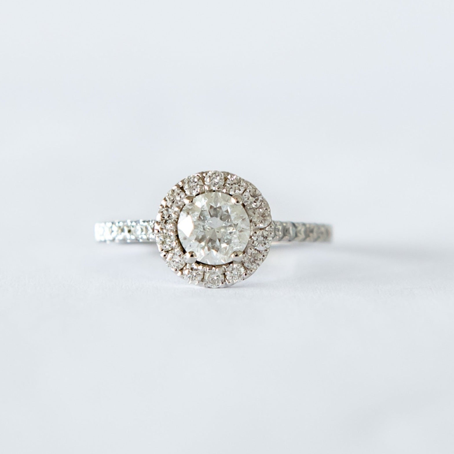 18ct white gold ring with a 0,70ct round brilliant cut diamond as the centre stone and a halo of diamonds surrounding it.