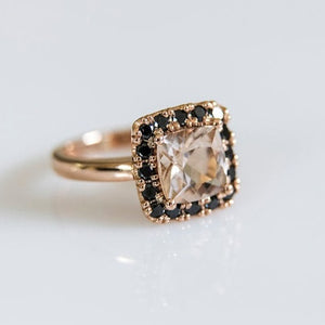side view of 18ct rose gold ring with morganite as the centre stone and a halo of black diamonds surrounding it.