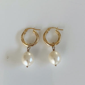 Gold huggie earrings with pearl drops.