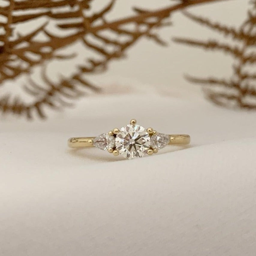 18ct yellow gold trilogy ring with a 0.6ct centre stone, flanked by two smaller pear cut diamonds