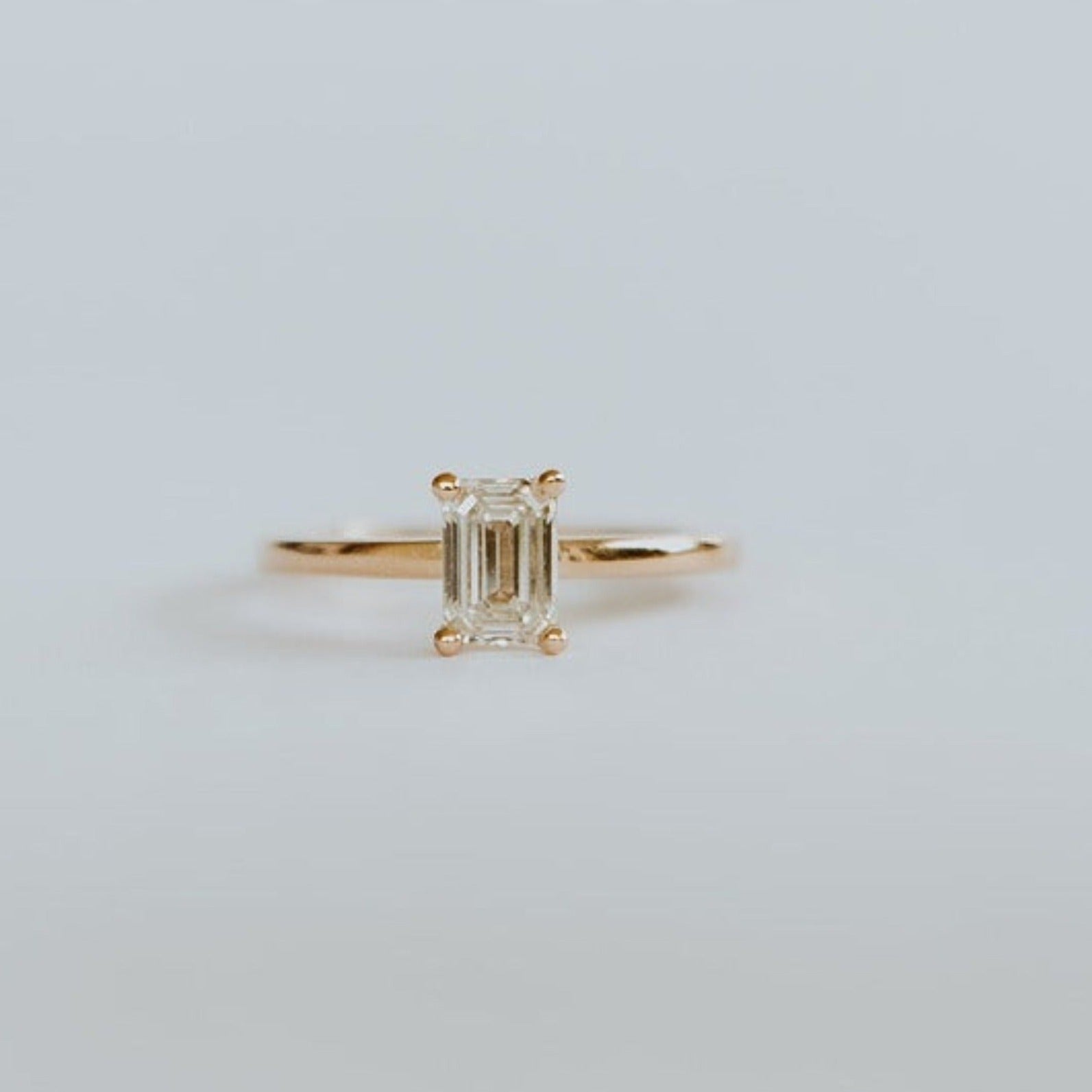 18ct yellow gold solitaire ring with 0,72ct claw set emerald cut diamond with a fine rounded band