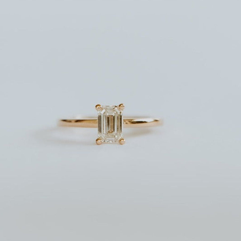 18ct yellow gold solitaire ring with 0,72ct claw set emerald cut diamond with a fine rounded band