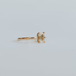 Side view of 18ct yellow gold solitaire ring with 0,72ct claw set emerald cut diamond with a fine rounded band